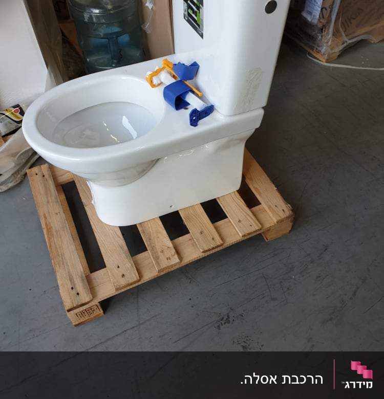 אסלה לבנה על משטח עץ עם חלקי התקנה